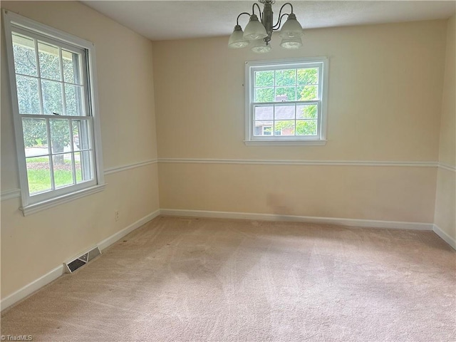 empty room with visible vents, a healthy amount of sunlight, and a notable chandelier