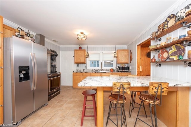 kitchen with light tile patterned floors, a peninsula, appliances with stainless steel finishes, and a breakfast bar