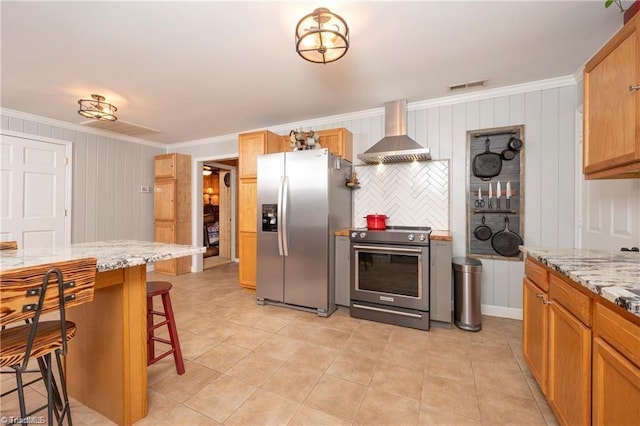 kitchen with ornamental molding, stainless steel appliances, wall chimney range hood, and visible vents