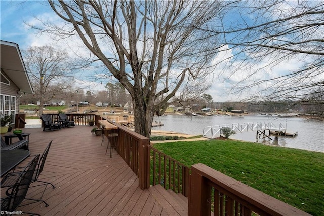 wooden deck with a lawn, a water view, and a dock