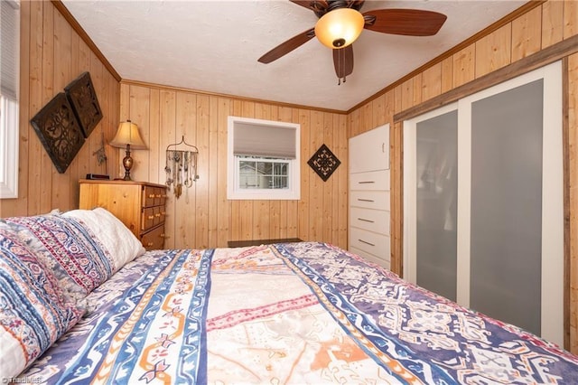 bedroom featuring ceiling fan, wood walls, and crown molding