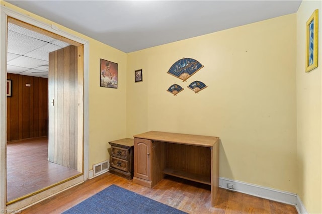 interior space featuring a drop ceiling and light hardwood / wood-style flooring