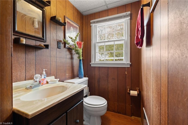 bathroom featuring vanity, hardwood / wood-style flooring, toilet, and wooden walls