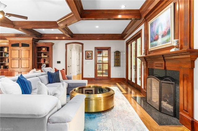 living room with crown molding, coffered ceiling, a fireplace, beamed ceiling, and light wood-type flooring