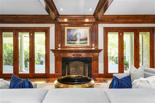 living room with beam ceiling, hardwood / wood-style flooring, a healthy amount of sunlight, and a fireplace