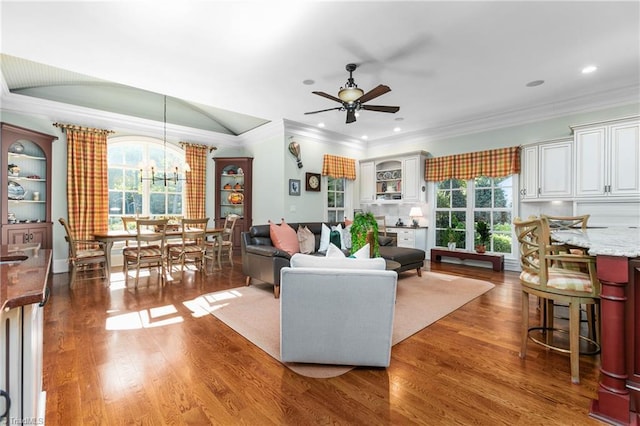 living room featuring dark wood-type flooring, crown molding, and ceiling fan with notable chandelier