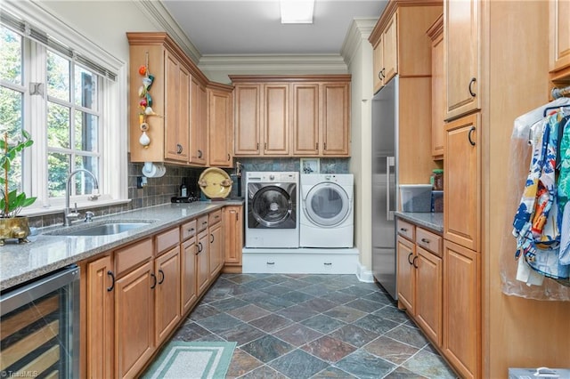 laundry area featuring wine cooler, sink, cabinets, separate washer and dryer, and ornamental molding