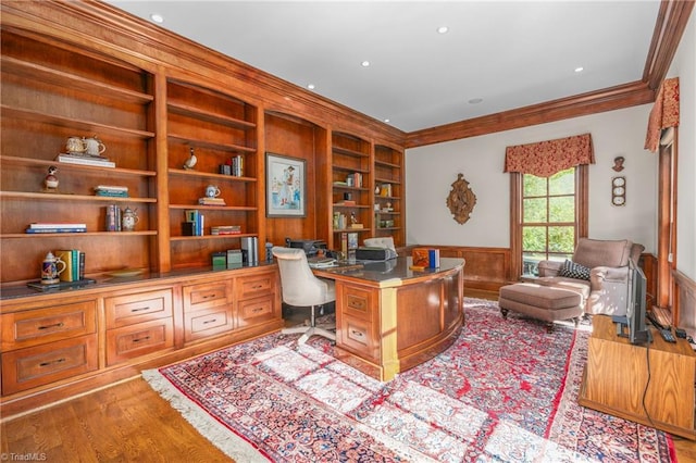 office space with crown molding, built in desk, built in features, and light wood-type flooring