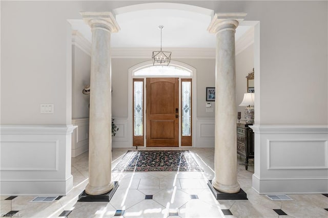 entryway featuring light tile patterned flooring, crown molding, and ornate columns