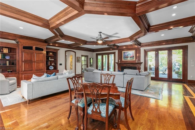 dining space with coffered ceiling, a healthy amount of sunlight, and light wood-type flooring