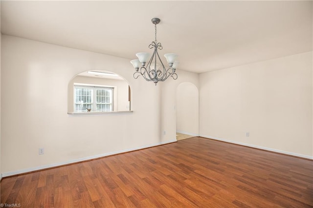 empty room featuring hardwood / wood-style floors and a notable chandelier