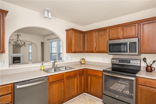 kitchen with stainless steel appliances, sink, and a notable chandelier