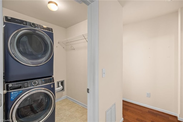 laundry room featuring stacked washer and dryer and light hardwood / wood-style floors