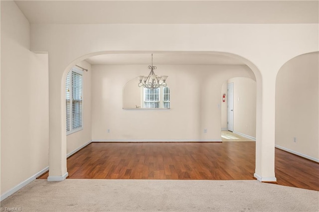 unfurnished room featuring wood-type flooring and a notable chandelier