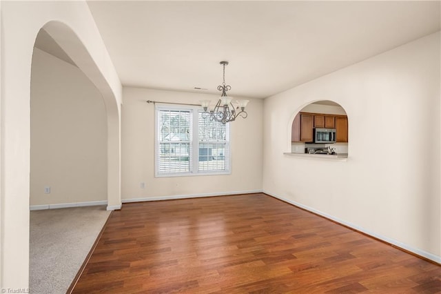 unfurnished dining area featuring an inviting chandelier and wood-type flooring