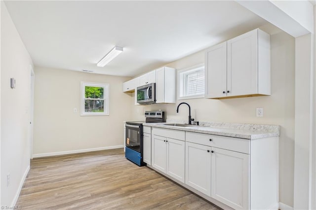 3885 Leo St, Winston-Salem, NC 27105 - kitchen with appliances with stainless steel finishes, light countertops, light wood-style flooring, and white cabinets