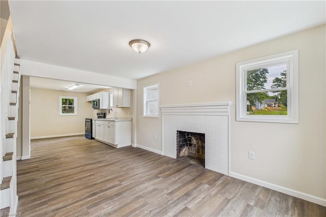 3885 Leo St, Winston-Salem, NC 27105 - unfurnished living room featuring light wood-style floors and a brick fireplace