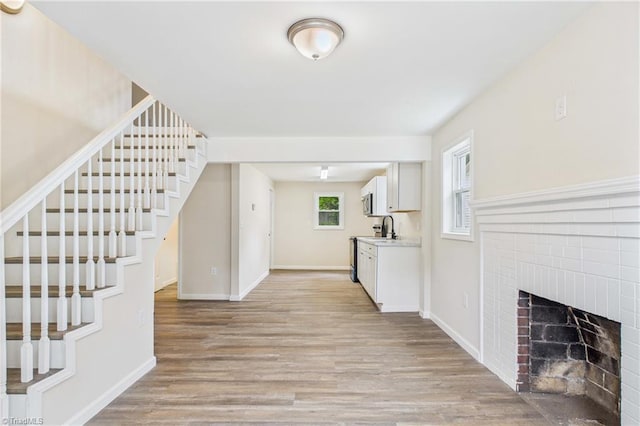 3885 Leo St, Winston-Salem, NC 27105 - kitchen featuring light wood-style flooring, a fireplace, white cabinets, light countertops, and stainless steel microwave