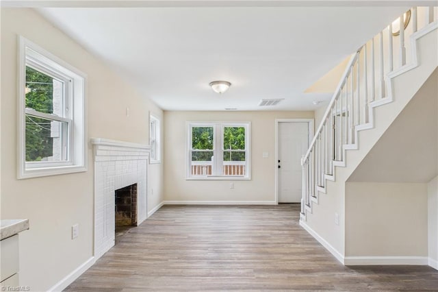 3885 Leo St, Winston-Salem, NC 27105 - unfurnished living room featuring wood finished floors, a brick fireplace, and stairs