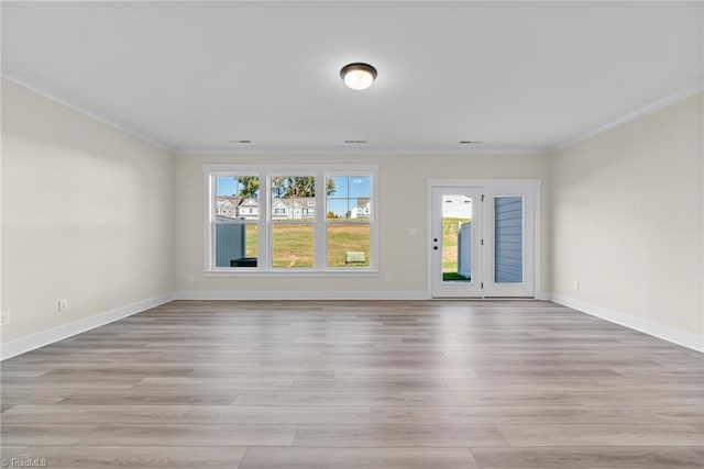 unfurnished room featuring ornamental molding, light wood-style floors, and baseboards