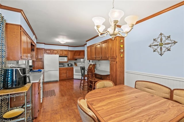 dining area featuring crown molding, sink, an inviting chandelier, and dark hardwood / wood-style flooring