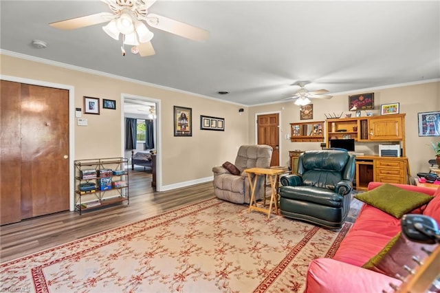 living room featuring ceiling fan, wood-type flooring, ornamental molding, and built in desk