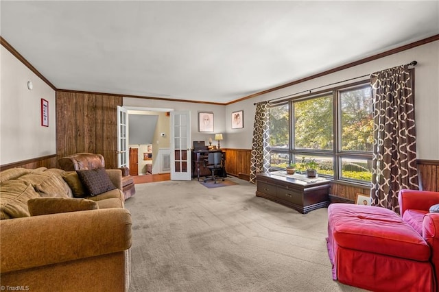 living room with wood walls, french doors, ornamental molding, and carpet floors