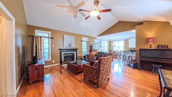 5110 Hartridge Way, Greensboro, NC 27407 - living room with ceiling fan, wood finished floors, vaulted ceiling, a glass covered fireplace, and baseboards
