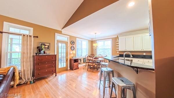 5110 Hartridge Way, Greensboro, NC 27407 - kitchen with a breakfast bar area, white cabinetry, light wood-type flooring, and healthy amount of natural light