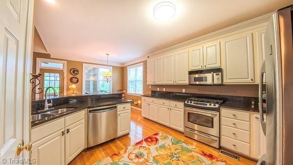 5110 Hartridge Way, Greensboro, NC 27407 - kitchen with appliances with stainless steel finishes, a sink, light wood-style flooring, dark countertops, and pendant lighting