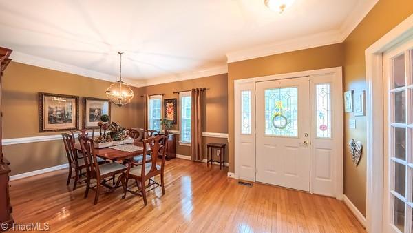 5110 Hartridge Way, Greensboro, NC 27407 - dining area featuring light wood-type flooring, a chandelier, ornamental molding, and baseboards