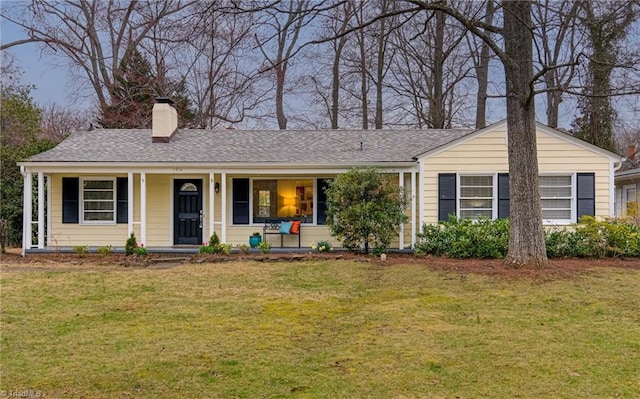 ranch-style home with a chimney, covered porch, and a front lawn