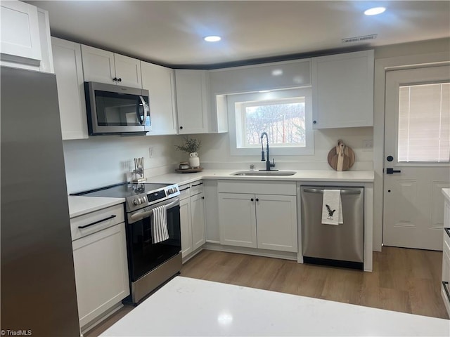 kitchen featuring white cabinetry, appliances with stainless steel finishes, sink, and light hardwood / wood-style flooring