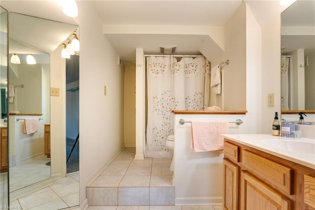 bathroom with toilet, tile floors, and vanity with extensive cabinet space