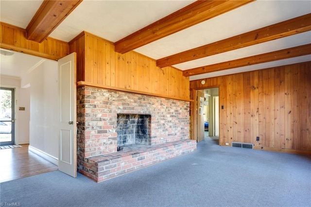 unfurnished living room with beam ceiling, a brick fireplace, and carpet floors