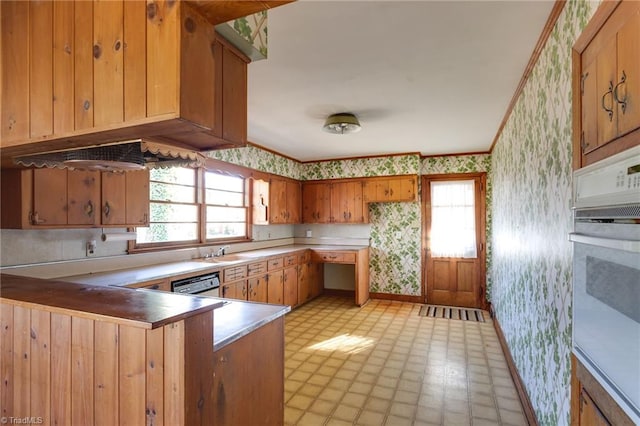 kitchen with stainless steel dishwasher, sink, white oven, and light tile floors