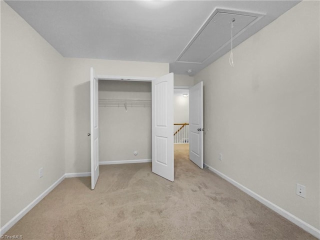 unfurnished bedroom featuring attic access, carpet, a closet, and baseboards