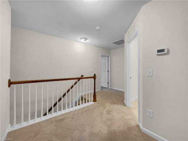 hallway featuring an upstairs landing, visible vents, carpet floors, and baseboards