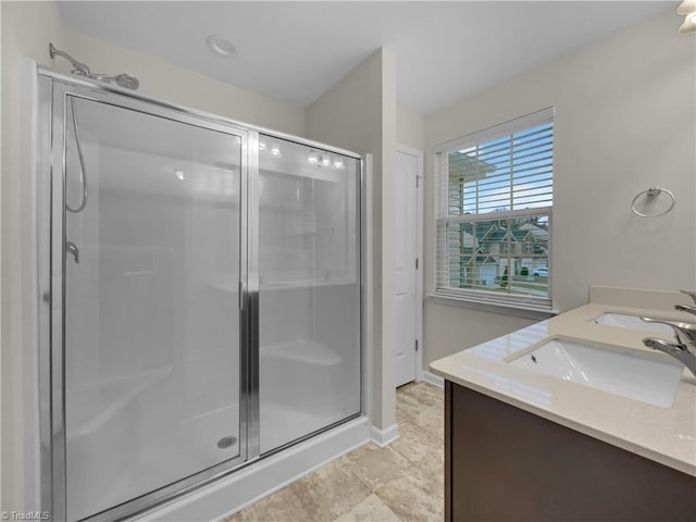 bathroom with a sink, baseboards, double vanity, and a shower stall