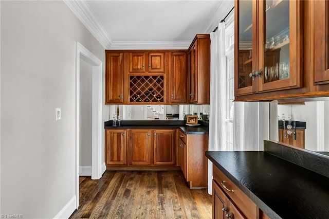 bar featuring indoor wet bar, baseboards, ornamental molding, and dark wood-type flooring