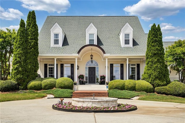 cape cod house with roof with shingles, ceiling fan, and a porch