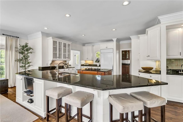 kitchen with a sink, a breakfast bar area, white cabinets, and tasteful backsplash