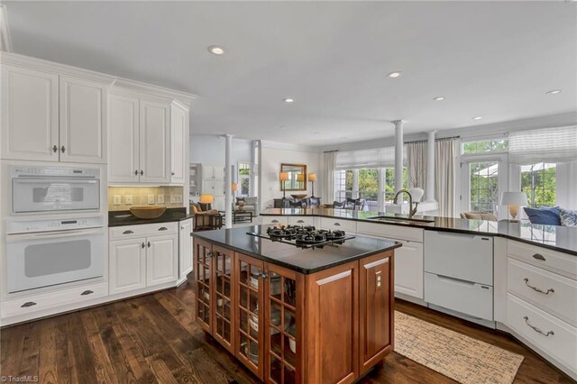 kitchen with a sink, dark wood-style flooring, dark countertops, and white appliances