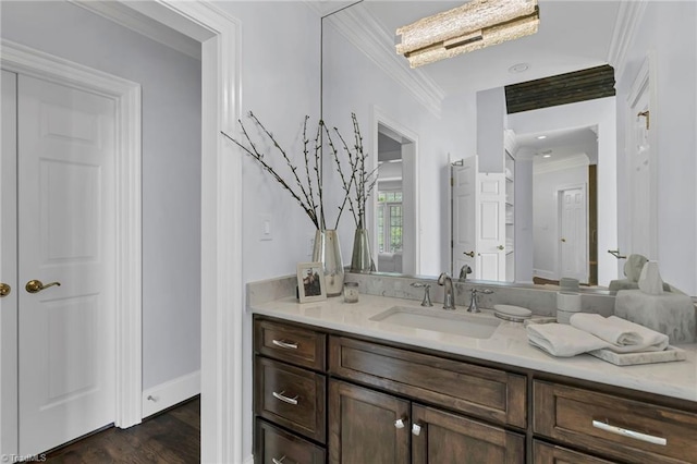 bathroom featuring crown molding, baseboards, wood finished floors, and vanity