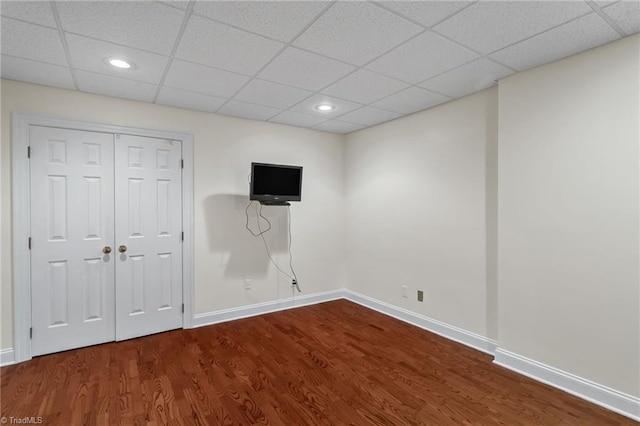 below grade area featuring baseboards, recessed lighting, wood finished floors, and a paneled ceiling