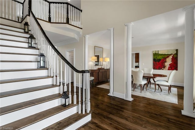 foyer with crown molding, baseboards, ornate columns, and wood finished floors