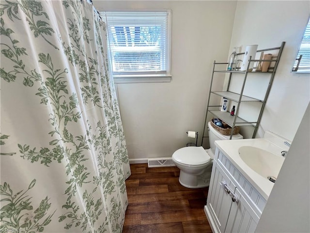 bathroom with visible vents, toilet, vanity, wood finished floors, and baseboards