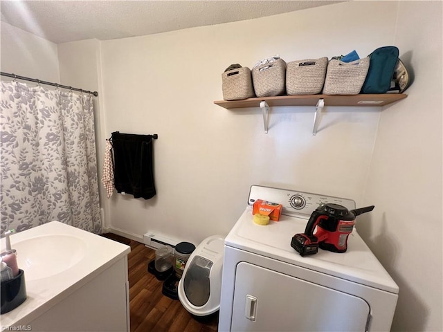 washroom with laundry area, a baseboard radiator, washer / clothes dryer, dark wood-type flooring, and a sink