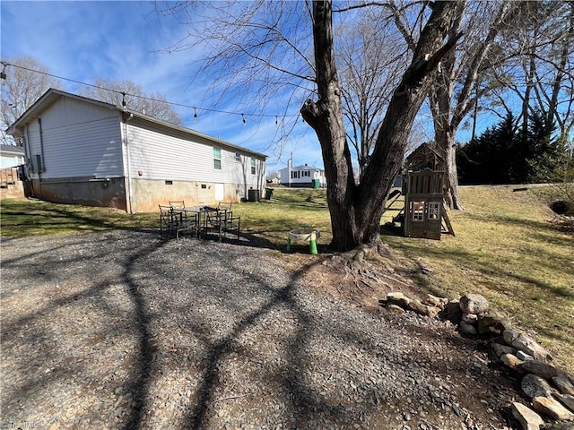 view of home's exterior with a yard, central AC, and a playground