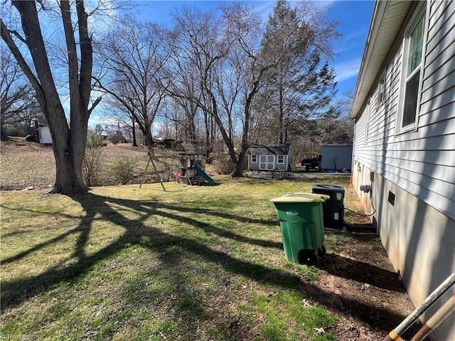 view of yard featuring an outbuilding, a playground, a storage unit, and central air condition unit